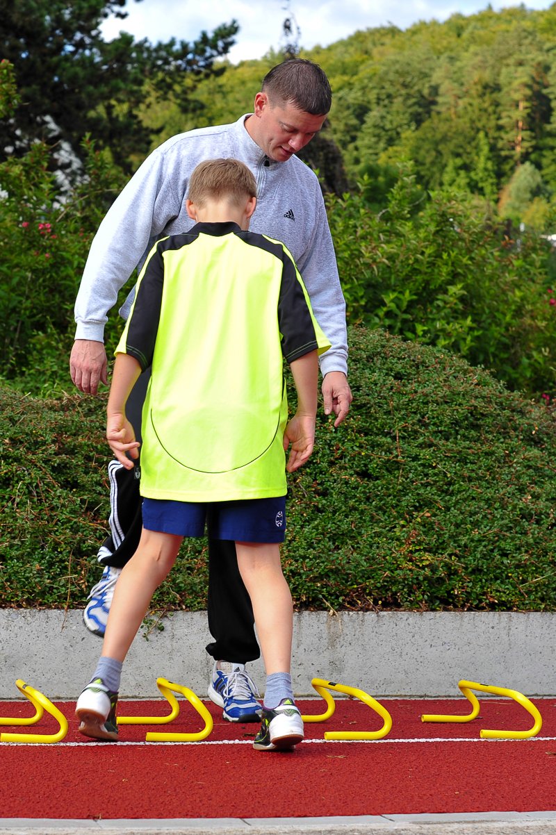 Sascha Göbl begleitet einen jungen Sportler beim Koordinationstraining mit Hürden.